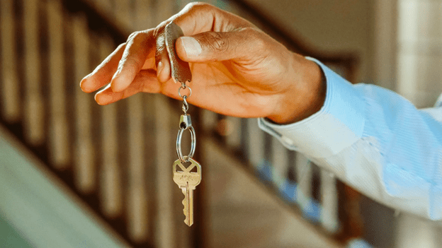 Man's hand holding a key on a keychain 